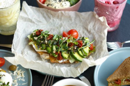 Foto de Tostadas exóticas con aguacate y tomates secos. Delicioso sándwich servido para el desayuno en un restaurante mediterráneo - Imagen libre de derechos