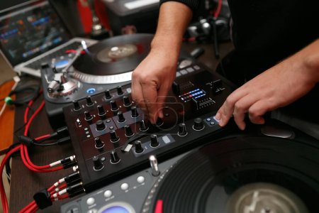Photo for Hip hop DJ mixing vinyl records on turn table in close up. Professional disc jockey plays music set with sound mixer and turntables - Royalty Free Image