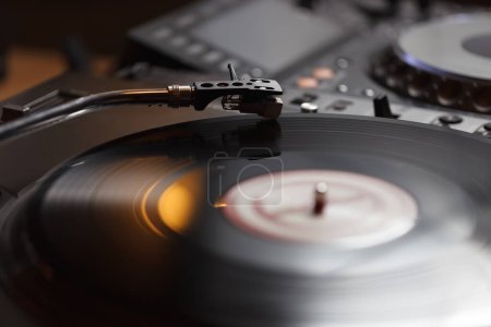 Giradiscos aguja reproducción de música de disco de vinilo analógico en primer plano. DJ profesional gire jugador de mesa girando récord en el escenario en el club nocturno