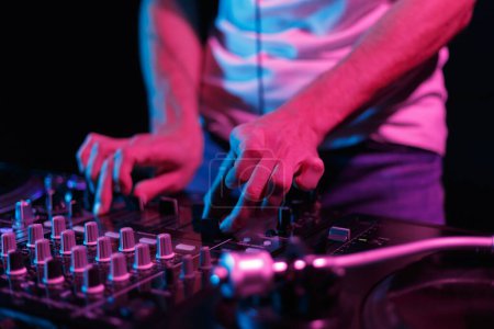 Photo for DJ playing music on party in night club. Close up photo of professional disc jockey mixing vinyl records with sound mixer device - Royalty Free Image