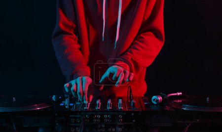 Photo for Hands of DJ mixing vinyl records with sound mixer in close up. Professinal club disc jokey plays set on party - Royalty Free Image