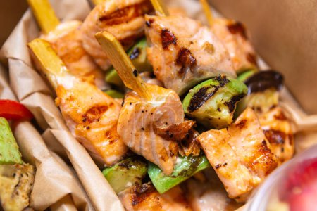 Téléchargez les photos : Filet de saumon cuit sur gril et livré pour le déjeuner d'affaires dans une boîte en carton. Plats à emporter gastronomiques fruits de mer - en image libre de droit