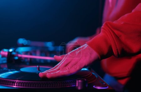 Téléchargez les photos : Hip hop DJ scratches enregistrer sur la table tournante. Main d'un disc jockey qui gratte un disque vinyle en gros plan - en image libre de droit