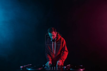 Foto de Club DJ mezclando discos de vinilo con mezclador de sonido en una fiesta en un club nocturno. Joven adulto masculino actuando como disc jockey - Imagen libre de derechos