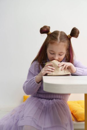 Téléchargez les photos : Petite fille affamée mangeant des pita souvlaki dans un fast-food grec. Un gamin affamé du primaire mange un sanwdich dans un café. - en image libre de droit