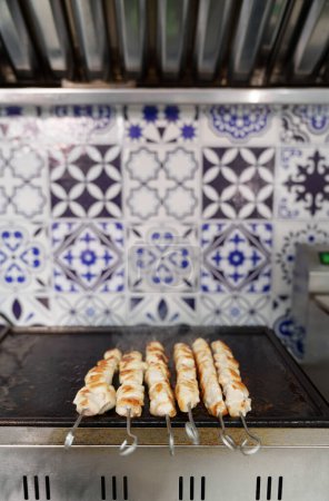 Photo for Chicken meat cooking on grill in commercial kitchen. White poultry fillet being cooked for lunch in Greek fast food restaurant - Royalty Free Image