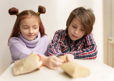 Photo for Elementary age kids eating fast food for in a restaurant. Handsome 11 year old boy and cute 9 year old girl with ponytails enjoying the lunch together - Royalty Free Image