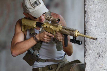 Foto de Soldado ucraniano apuntando al objetivo con un rifle de asalto. Fuerte joven militar haciendo entrenamiento táctico al aire libre con arma automática moderna - Imagen libre de derechos