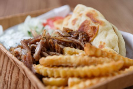 Photo for Traditional Greek souvlaki meat and pita served with white tzatziki sauce and French fries in recyclable paper plate for take away - Royalty Free Image