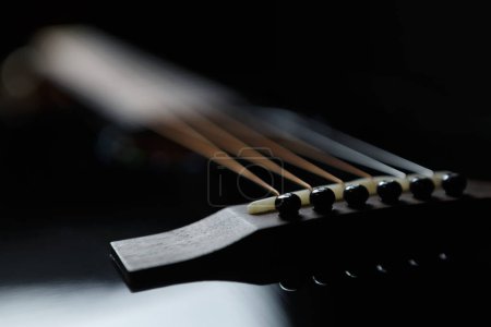 Photo for Black acoustic guitar sadle and fixing pegs in focus. Professional musical instrument with metal strings - Royalty Free Image
