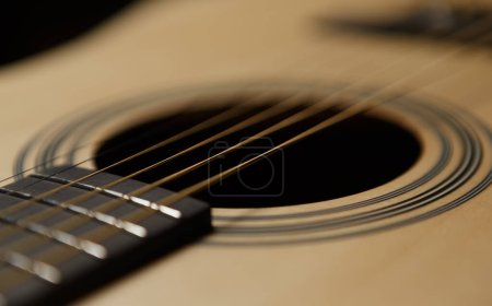 Guitarra acústica clásica en primer plano. Agujero de sonido y cuerdas de metal de instrumento musical profesional en foco