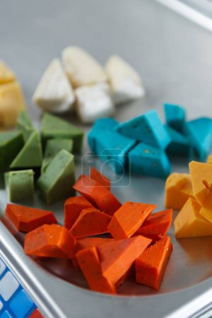 Foto de Surtido de quesos de colores en pesos. Trozos de productos lácteos multicolores para menú de aperitivo de vino - Imagen libre de derechos