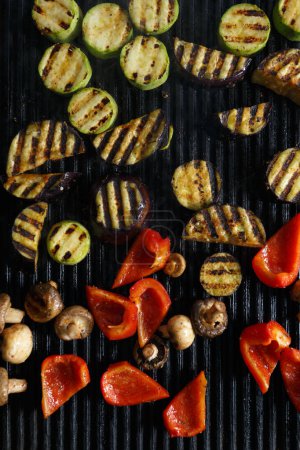 Photo for Grilled vegetables in flat lay. Hot grill pan surface with cooked zucchini, red bell pepers and mushrooms - Royalty Free Image