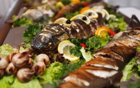 Téléchargez les photos : Poisson entier énorme cuit pour le dîner dans un restaurant de fruits de mer et servi avec des citrons et de la salade - en image libre de droit
