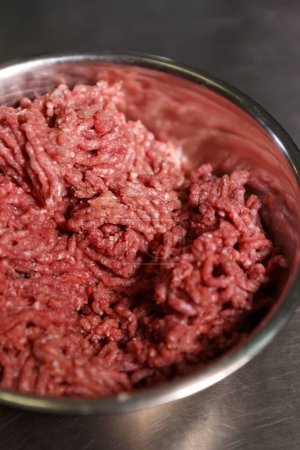 Téléchargez les photos : Viande hachée de bœuf hachée dans une casserole. Filet de vache rouge naturel préparé pour la cuisson dans une cuisine commerciale - en image libre de droit