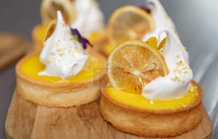 Foto de Tarta de pan corto decorada con limones secos y crema blanca. Deliciosos postres servidos en plato de madera para el almuerzo en una pastelería - Imagen libre de derechos