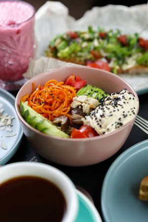 Photo for Poke bowl with healthy and natural ingredients served in a restaurant. Exotic lunch meal prepared with hummus dip, sliced avocado, cucumbers, Korean carrot and black sesame seeds - Royalty Free Image