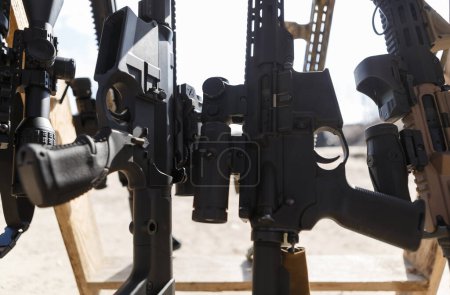 Foto de Fusiles de asalto estadounidenses modernos equipados con miras ópticas y lupas en el soporte de armas en el campo de tiro al aire libre - Imagen libre de derechos