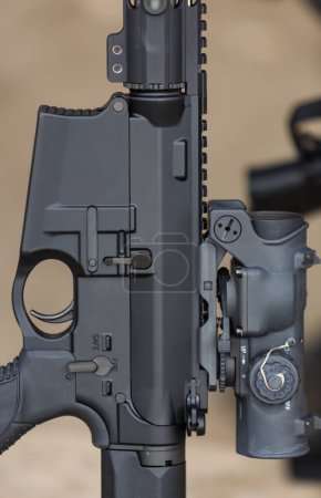 Foto de Fusil de asalto negro moderno con lupa montada. Arma americana automática estándar en un soporte en el campo de tiro - Imagen libre de derechos