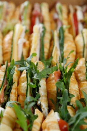 Photo for Large box of fresh croissants with arugula, vegetables and red fish delivered for food catering service on a venue - Royalty Free Image