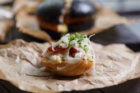Téléchargez les photos : Snack végétarien exotique à la tomate séchée et à l'oignon vert servi sur du papier parchemin dans un restaurant haut de gamme - en image libre de droit