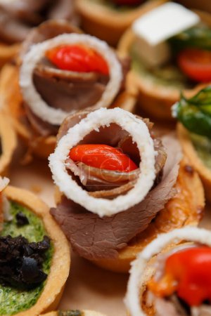 Photo for Exotic antipasti snacks delivered for food catering in a cardboard box. Delicious canape with veal meat and marinated red pepper decorated with onion rings - Royalty Free Image