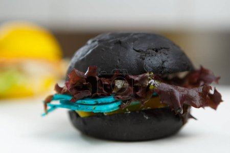 Téléchargez les photos : Burger noir exotique aux feuilles de basilic et fromage bleu - en image libre de droit