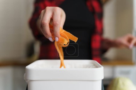 Photo for Female hand throwing food scraps into compost bin. Woman recycling organic waste in a bokashi container at home. Person using compostable leftovers for composting - Royalty Free Image