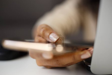 Téléchargez les photos : Femme noire utilisant l'application smartphone moderne. Femme à la peau foncée tapant sms dans l'application de téléphone mobile - en image libre de droit