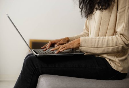 Téléchargez les photos : Femme écrivain freelance tapant du texte sur le clavier du portable. Femme noire travaillant sur un ordinateur portable à la maison - en image libre de droit