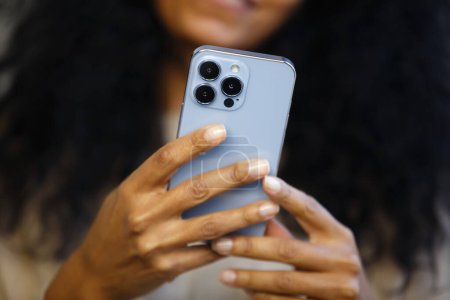 Black woman using mobile phone. African female person browsing app on modern smartphone. Download stock photo of new cellphone with triple camera