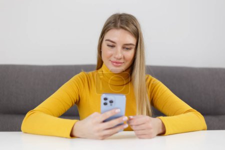 Foto de Mujer rubia feliz navegación aplicación móvil en el teléfono inteligente azul moderno. Chica ucraniana alegre utilizando el teléfono celular para la comunicación - Imagen libre de derechos