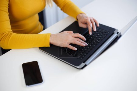 Téléchargez les photos : Femme écrivain freelance tapant du texte sur le clavier de l'ordinateur portable. Programmeur femelle codage sur ordinateur portable - en image libre de droit