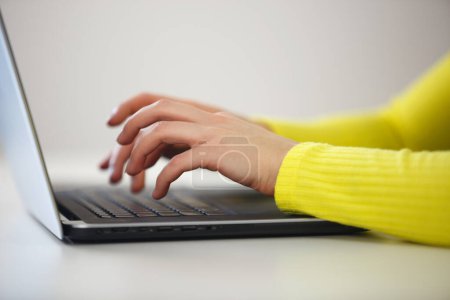 Téléchargez les photos : Femme tapant du texte sur le clavier de l'ordinateur. Jeune femme travaillant sur un ordinateur portable dans le bureau. Copier écrivain personne travaille sur ordinateur portable moderne à la maison - en image libre de droit