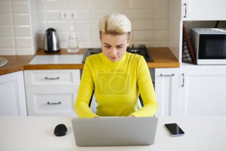 Foto de Mujer blanca de pelo corto escribiendo texto en el teclado del portátil. Tom chico persona que trabaja en el ordenador portátil en casa - Imagen libre de derechos