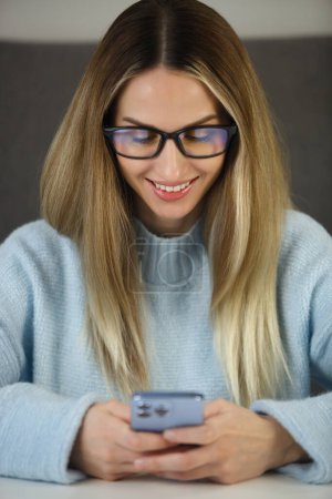 Foto de Mujer blanca feliz escribiendo sms mensaje en el teléfono móvil. Alegre persona femenina que se comunica en línea en la aplicación para teléfonos inteligentes - Imagen libre de derechos