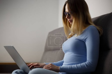 Foto de Mujer trabajando en el portátil por la noche. Escritor independiente escribiendo texto en una computadora portátil moderna en casa. Programador femenino codificación en el ordenador - Imagen libre de derechos