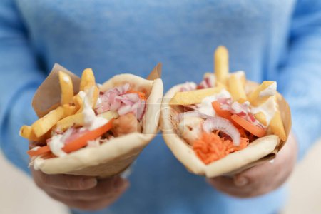 Photo for Woman holding two gyros pita sandwiches in hands. Female person holds traditional Greek fast food with grilled meat, fries and tzatziki sauce wrapper in a pita bread - Royalty Free Image