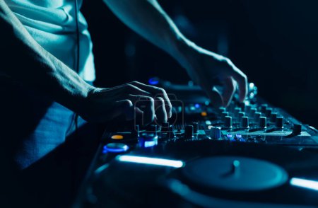Foto de Techno fiesta DJ tocando música con mezclador de sonido y tocadiscos. Club disc jockey mezclando pistas musicales en la fiesta de cerca, se centran en las manos - Imagen libre de derechos