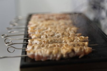 Foto de Filete de carne de cerdo cocinado en brochetas en una parrilla caliente en una cocina comercial - Imagen libre de derechos