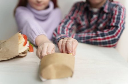 Téléchargez les photos : Deux gamins blancs qui mangent des frites pour le déjeuner. Deux petits enfants prenant des chips de pommes de terre de la boîte - en image libre de droit