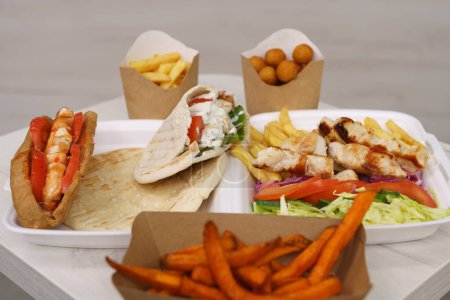 Téléchargez les photos : Restauration rapide grecque traditionnelle servie sur table dans un café. Sandwich Gyros, pita souvlaki, kalamaki et frites préparés pour le déjeuner dans un restaurant - en image libre de droit