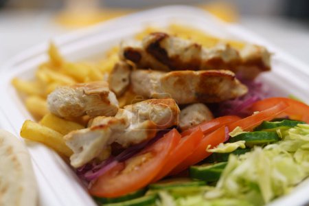 Foto de Lleve el kalamaki servido en una lonchera en un restaurante griego de comida rápida. Plato tradicional de carne mediterránea - Imagen libre de derechos