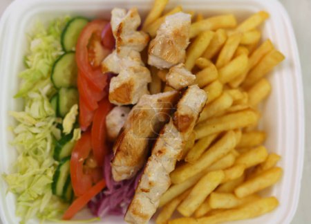 Téléchargez les photos : Boîte à lunch avec plat grec kalamaki préparé avec viande souvlaki, frites et légumes frais. - en image libre de droit