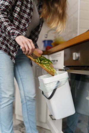 Téléchargez les photos : Femme jetant des pelures de nourriture compostables dans une poubelle bokashi avec du compost et du son - en image libre de droit