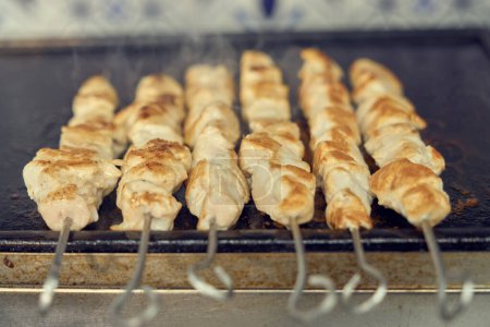 Photo for Pork meat on metal skewers being cooked in a grill. Traditional Greek fast food preparation - Royalty Free Image