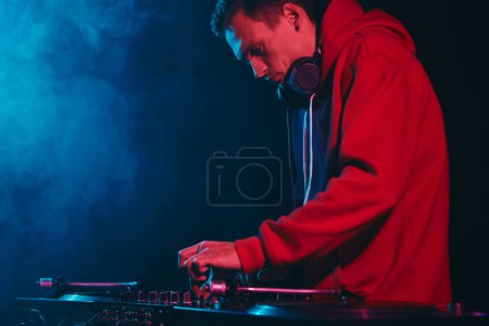 Foto de Hip hop DJ mezclando discos de vinilo en el escenario. Cool joven disc jockey tocando música en club nocturno oscuro - Imagen libre de derechos