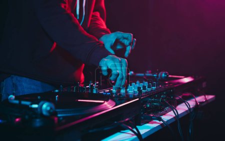 Téléchargez les photos : DJ de club mélangeant ensemble de musique. Jokey disque professionnel jouant hip hop sur une fête - en image libre de droit
