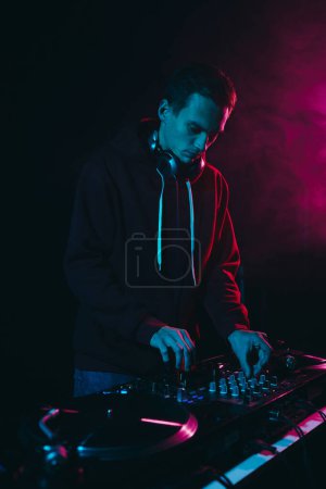 Photo for Young white man performing as a DJ in night club. Professional disk jokey mixing vinyl records on a concert - Royalty Free Image