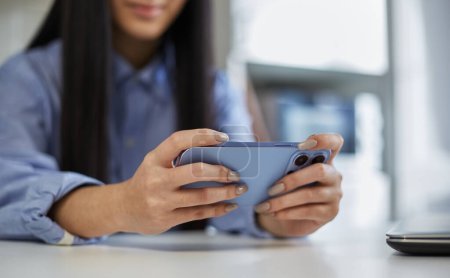 Foto de Chica joven jugando juegos en línea en un teléfono inteligente. Persona femenina irreconocible juega videojuegos en un gadget moderno - Imagen libre de derechos